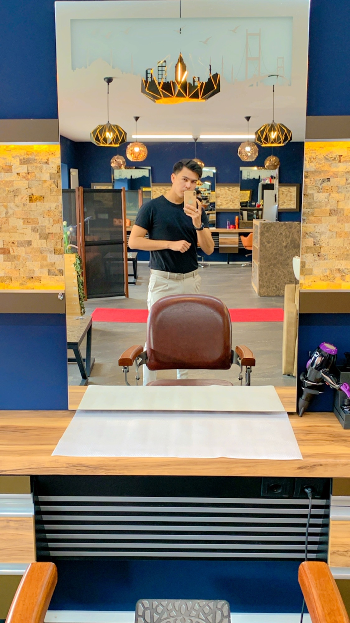 Arbeitsplatz mit braunem Barberstuhl, Spiegel und Kronleuchtern